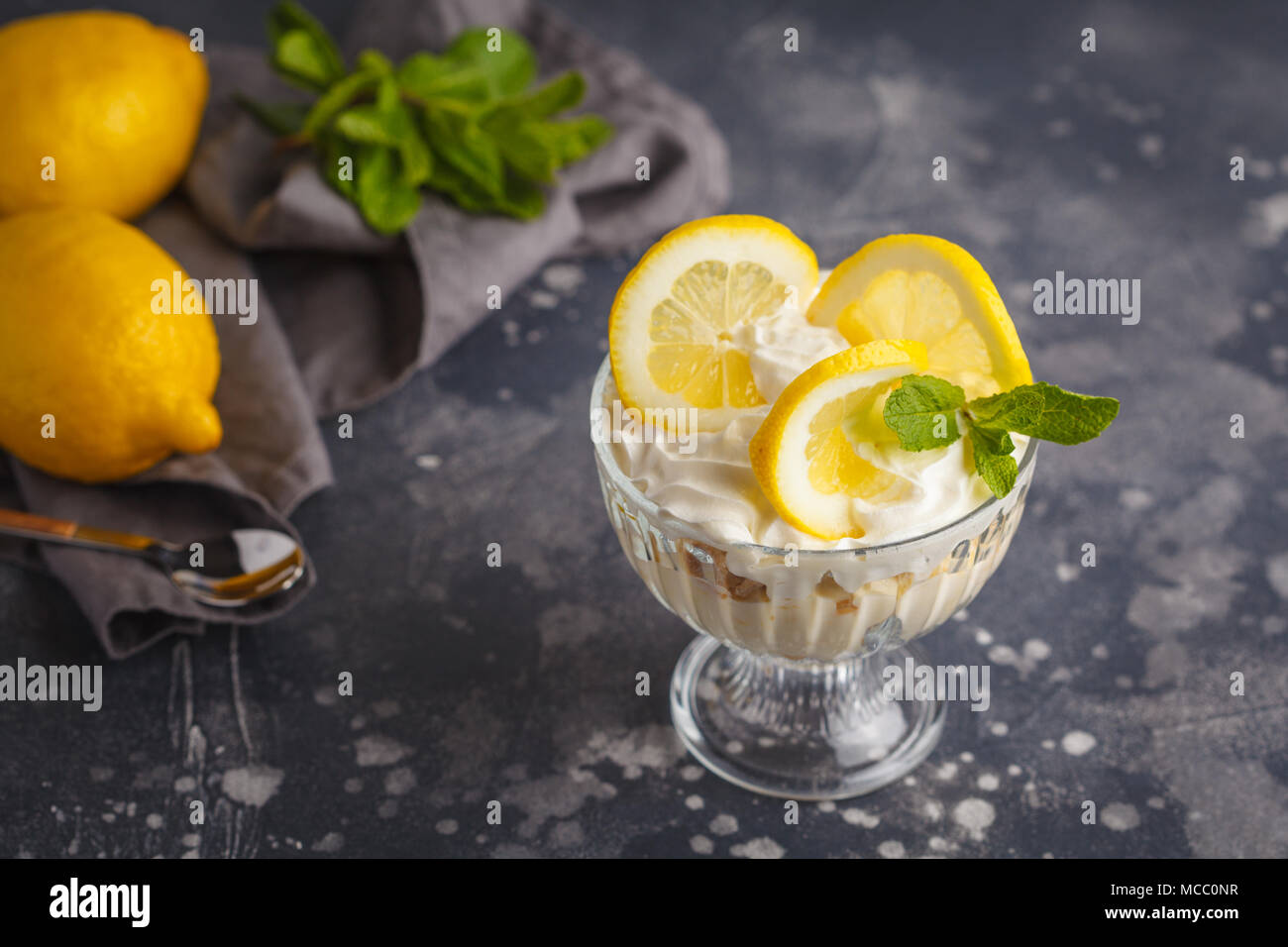Dessert Citron, citron trifle, gâteau au fromage, crème fouettée, parfait. Mousse de fruits en verre sur un fond sombre. Banque D'Images