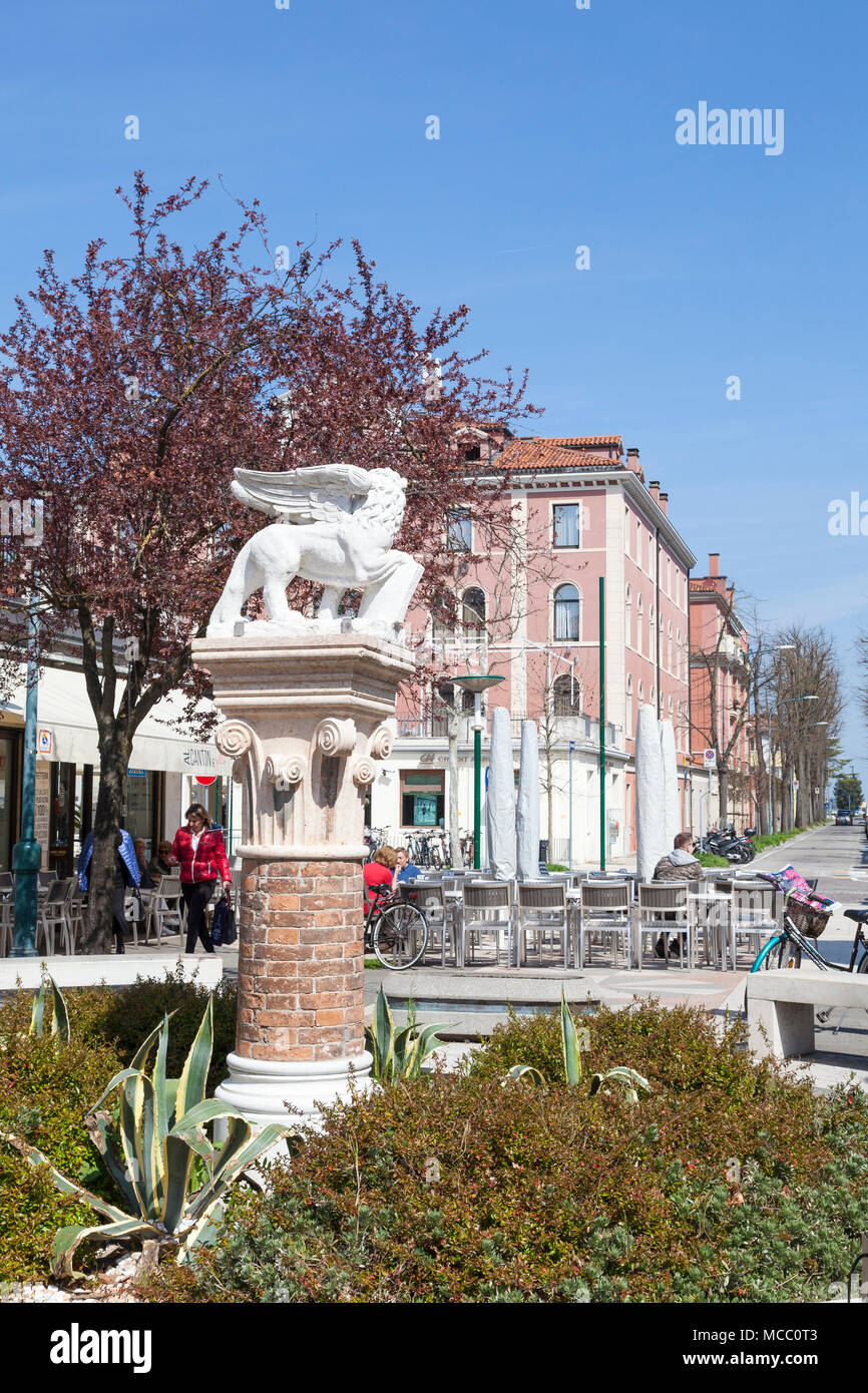 Le lion ailé statue sur l'île du Lido, (Lido di Venezia, Venice Lido) Venise, Vénétie, Italie avec des gens de manger dans un restaurant off Granviale Santa Ma Banque D'Images