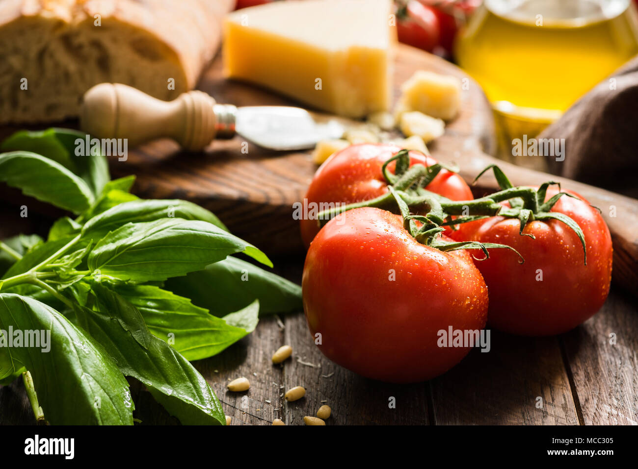 Arrière-plan de cuisine italienne avec des tomates sur vigne, basilic, huile d'olive, parmesan et du pain ciabatta. Gros plan, selective focus Banque D'Images