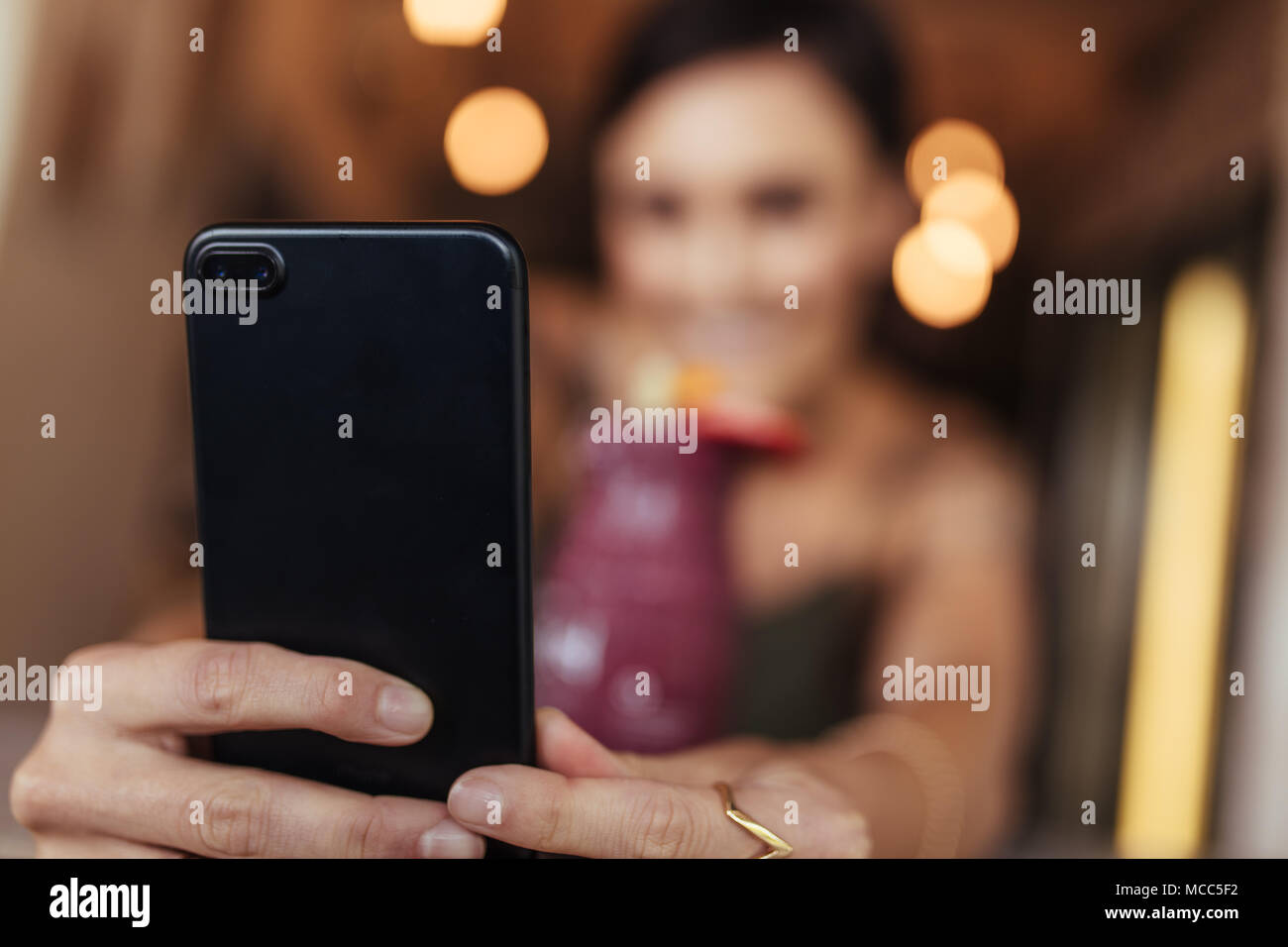 Image floue d'une femme prenant une avec un smoothie selfies mis sur la table à l'aide d'un téléphone mobile. Prise de photos pour l'alimentation blogger son blog à la maison. Banque D'Images