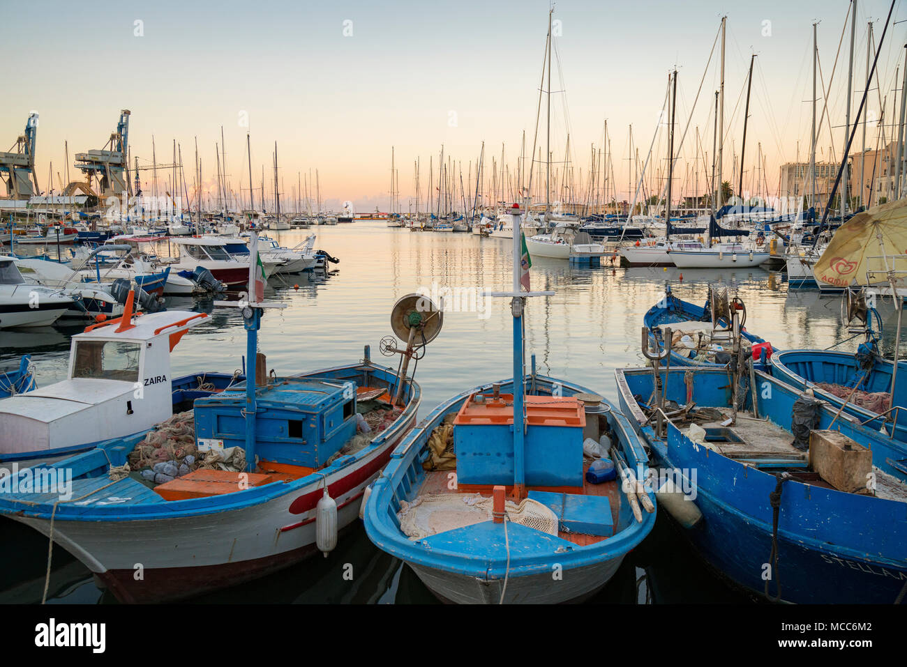 Vieux bateaux de pêche et de voiliers modernes dans l'ancien 'La Cala' port et marina à Palerme, Sicile, Italie, alors que le soleil se couche sur une journée d'été en août. Banque D'Images