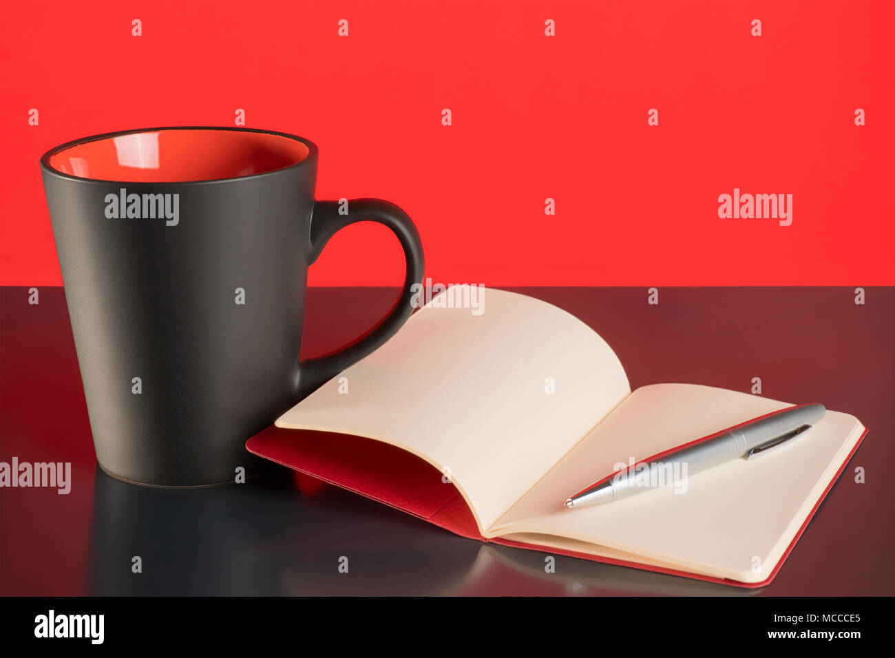 Tasse à café, ouvrir carnet et un stylo noir sur fond rouge et table Banque D'Images