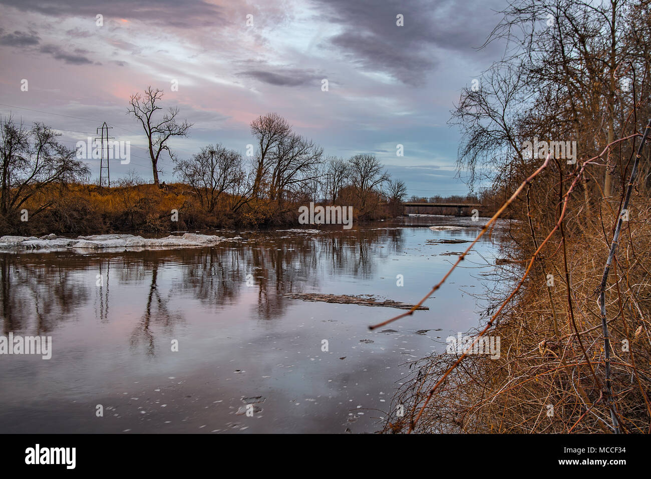 Coucher du soleil sur la rivière Mohawk dans l'État de New York pendant que la glace a fondu et le reflet des arbres sur l'eau. Banque D'Images
