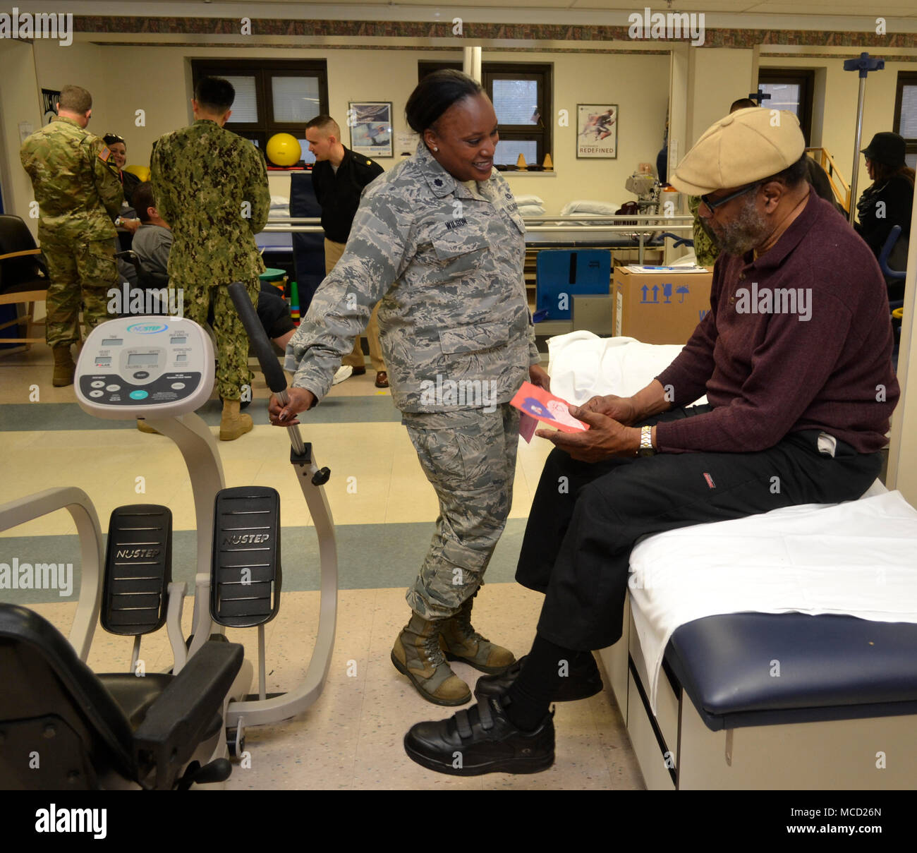 Le Lieutenant-colonel de l'Armée de l'air Chiriga Wilson présente une carte de remerciement à un patient recevant la thérapie physique au Caporal Michael J. Crescenz Veterans Affairs Medical Center, le 12 février 2018 à Philadelphie. Des bénévoles de l'appui de troupes DLA a visité le centre médical à l'appui de la Salute to Patients Anciens Combattants 7. Banque D'Images