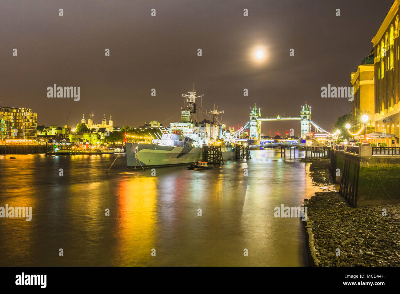 Le HMS Belfast, la Tamise, le Tower Bridge et la Tour de Londres vue de l'hôtel de ville de nuit de South Bank, Londres, Angleterre Royaume-uni avec des réflexions Banque D'Images