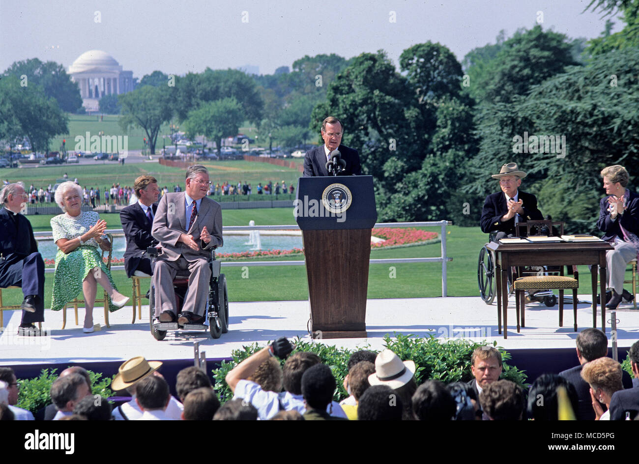 Le président des États-Unis George H. W. Bush rend commentaires avant de signer l'Americans with Disabilities Act de 1990 en loi au cours d'une cérémonie à la Maison Blanche à Washington, DC Le 26 juillet 1990. Sur la photo, sur scène, (de gauche à droite) : le révérend Harold Wilke, first lady Barbara Bush, vice-président américain Dan Quayle, Evan Kemp, le Président Bush, Justin Dart, et Sandra Parrino. La loi interdit la discrimination des employeurs sur le handicap. Credit : Ron Sachs/CNP /MediaPunch Banque D'Images