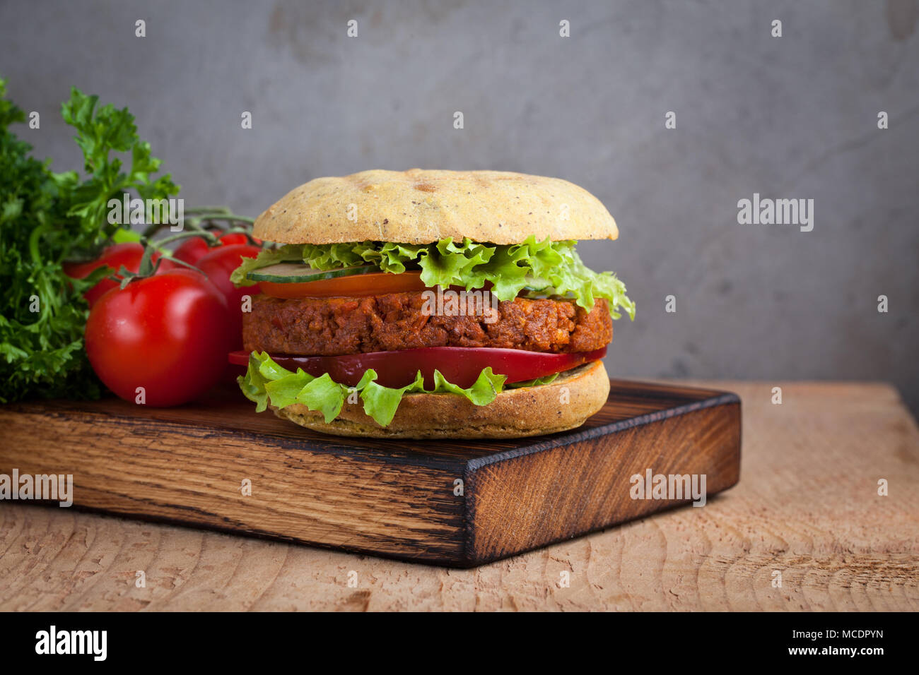 Fresh Burger végétalien avec tomates, concombres, laitue et végétalien escalope sur planche de bois. Banque D'Images