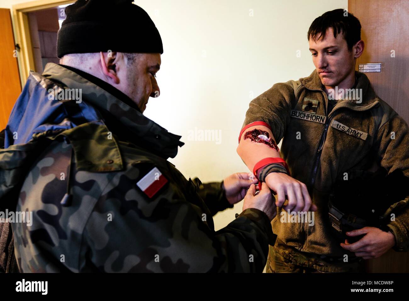 Un soldat polonais avec la 11e Division de cavalerie blindée (gauche), s'applique à une fausse blessure à la CPS de l'armée américaine. Dalton, un Buchhoprn Boerne, natif du Texas et un opérateur de systèmes de transmission multicanaux-responsable avec le 82e bataillon du génie de la Brigade Blindée, 2e Brigade Combat Team, 1re Division d'infanterie, au cours de la simulation d'un exercice de gestion de crise dans la région de Zagan, Pologne le 26 février 2018. La formation multinationale a été fait pour augmenter l'interopérabilité avec les premiers intervenants polonais et de forces armées alors qu'à l'appui de la résolution de l'Atlantique. (U.S. Photo de l'armée par la CPS. Hubert D. Delany III / 22e Public Mobile Banque D'Images