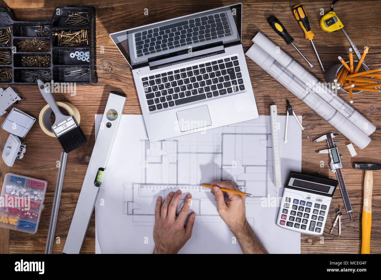 La main de l'architecture du plan de dessin avec l'ordinateur portable sur un bureau en bois Banque D'Images