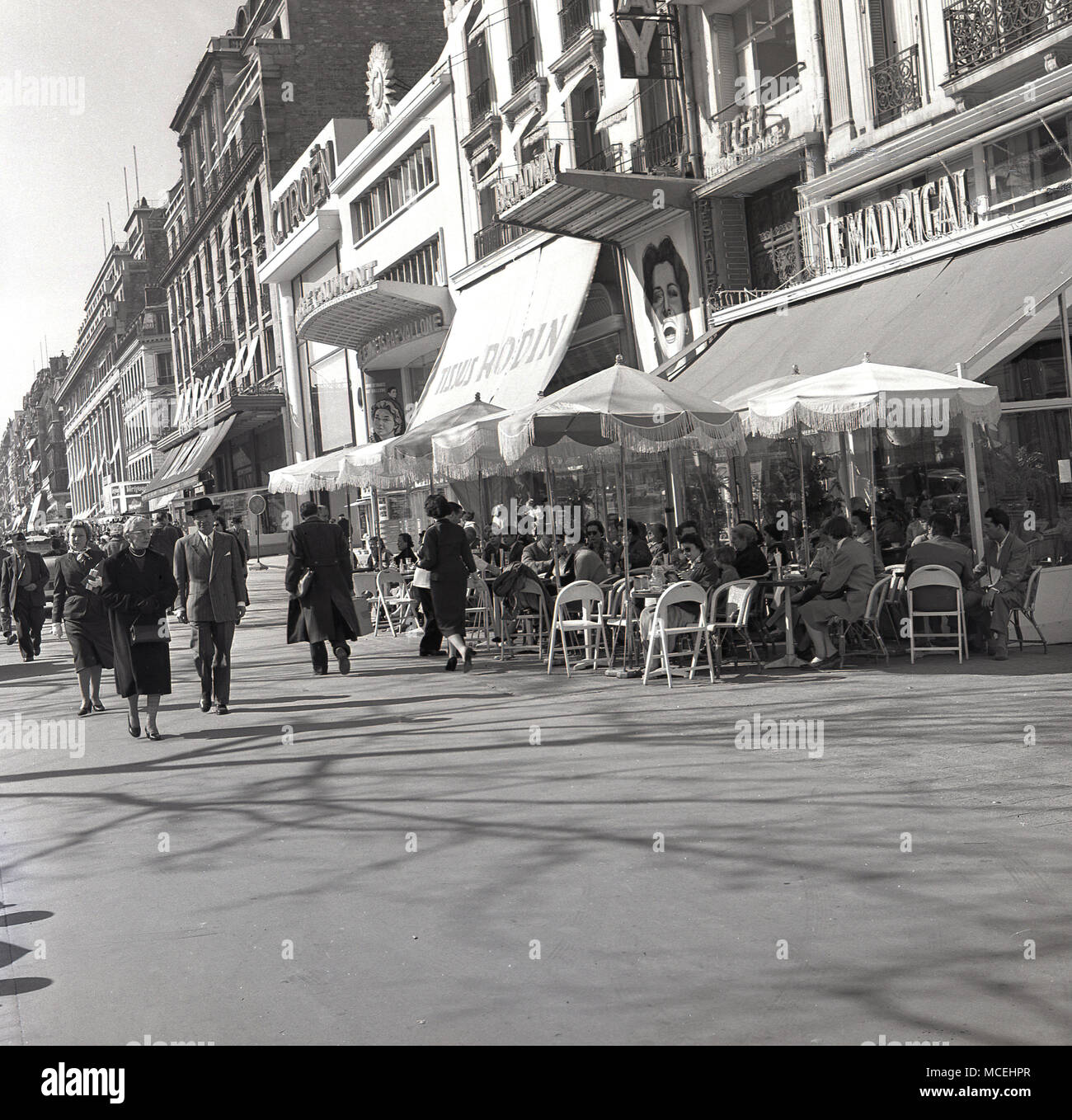Années 1950, historiques, printemps et parisiens à marcher le long de l'Avenue de Champs-Elysées, Paris, France après le café français "Le Madrigal" Banque D'Images