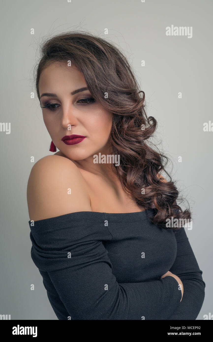 Portrait d'une charmante brunette avec de beaux cheveux bouclés dans une robe noire Banque D'Images