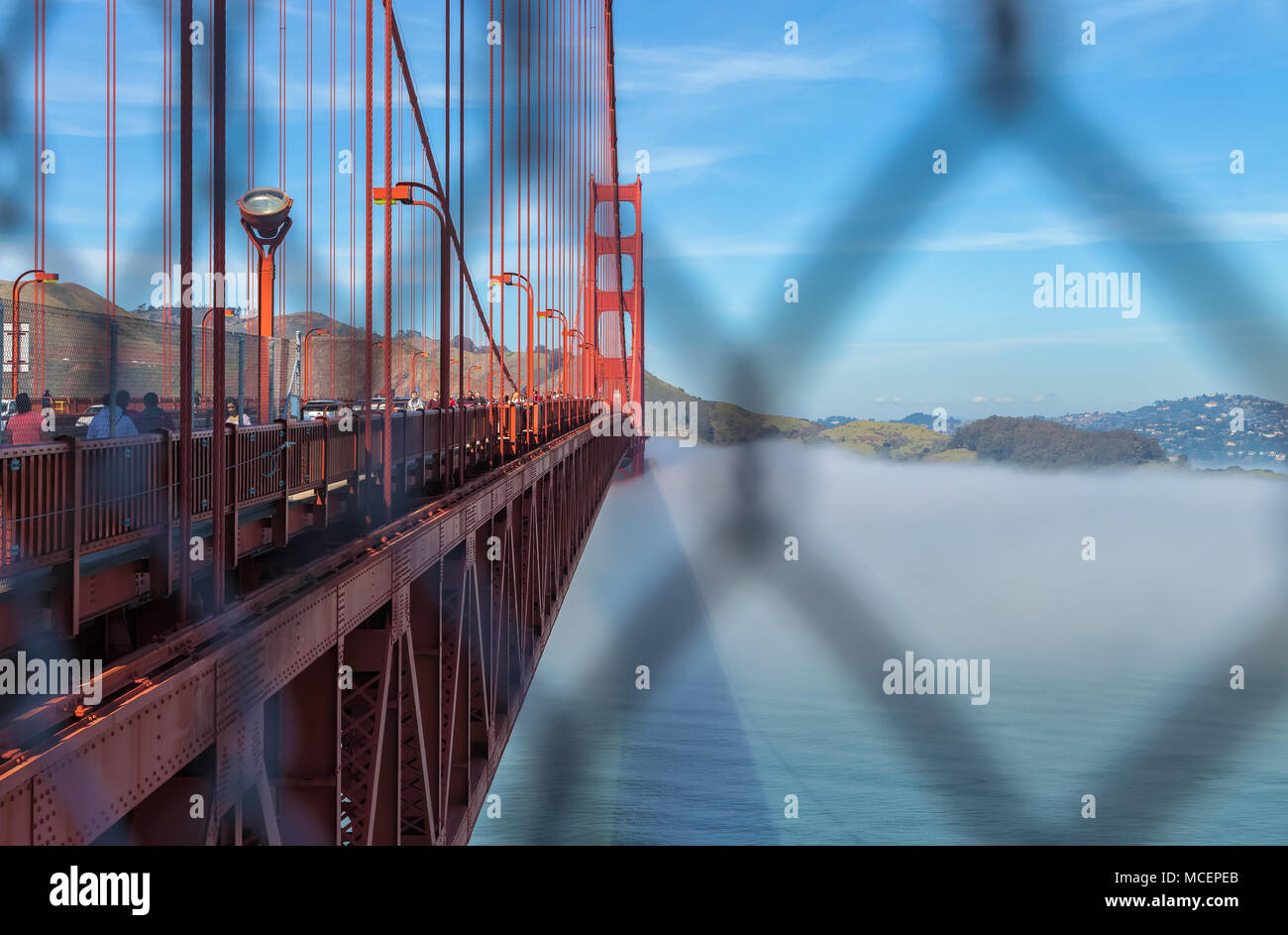 Vue sur le Golden Gate Bridge, avec le brouillard en dessous, à travers la barrière de sécurité, San Francisco, California, United States. Banque D'Images