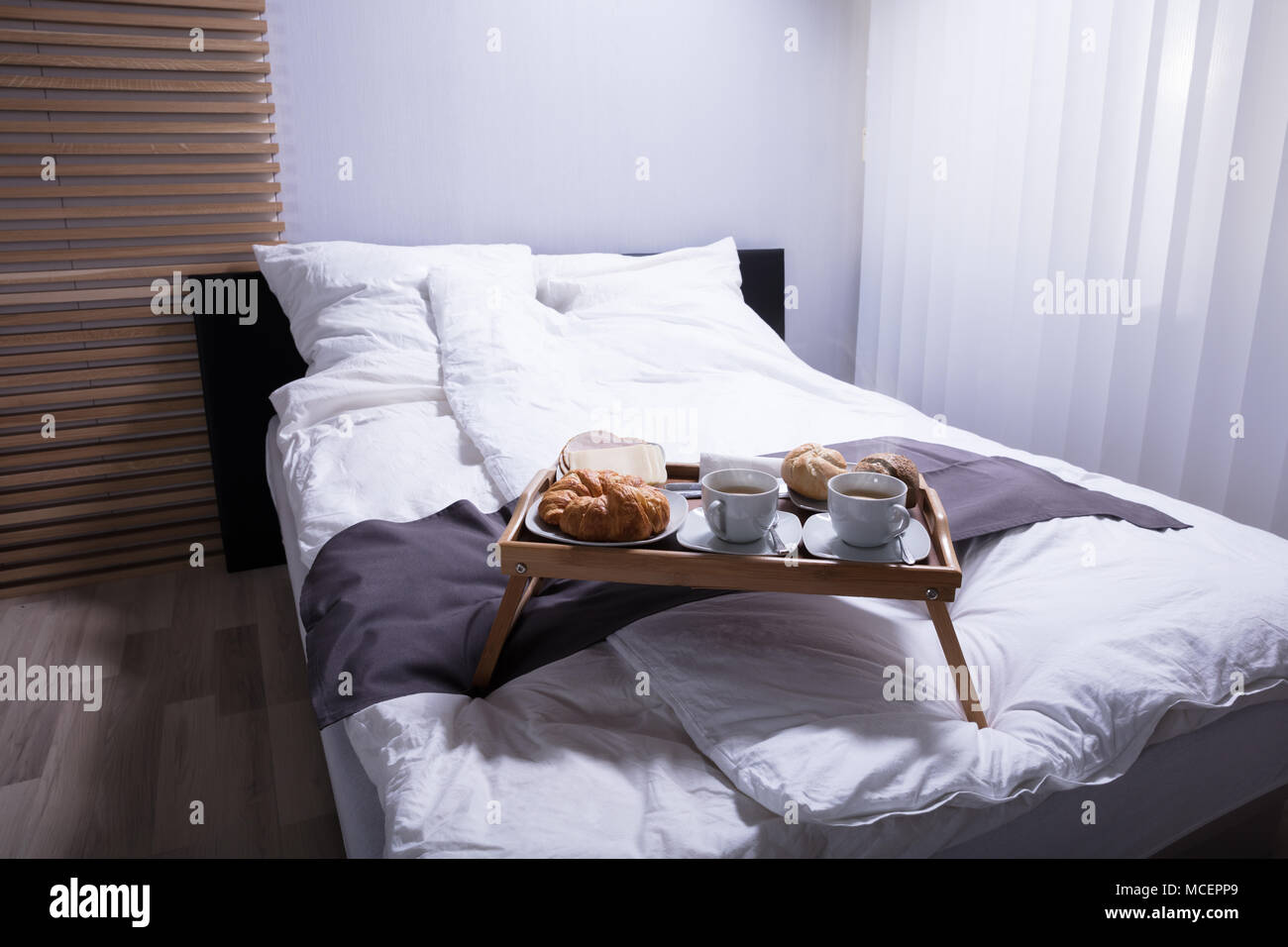 Des croissants frais et une tasse de thé sur le lit au petit déjeuner Banque D'Images