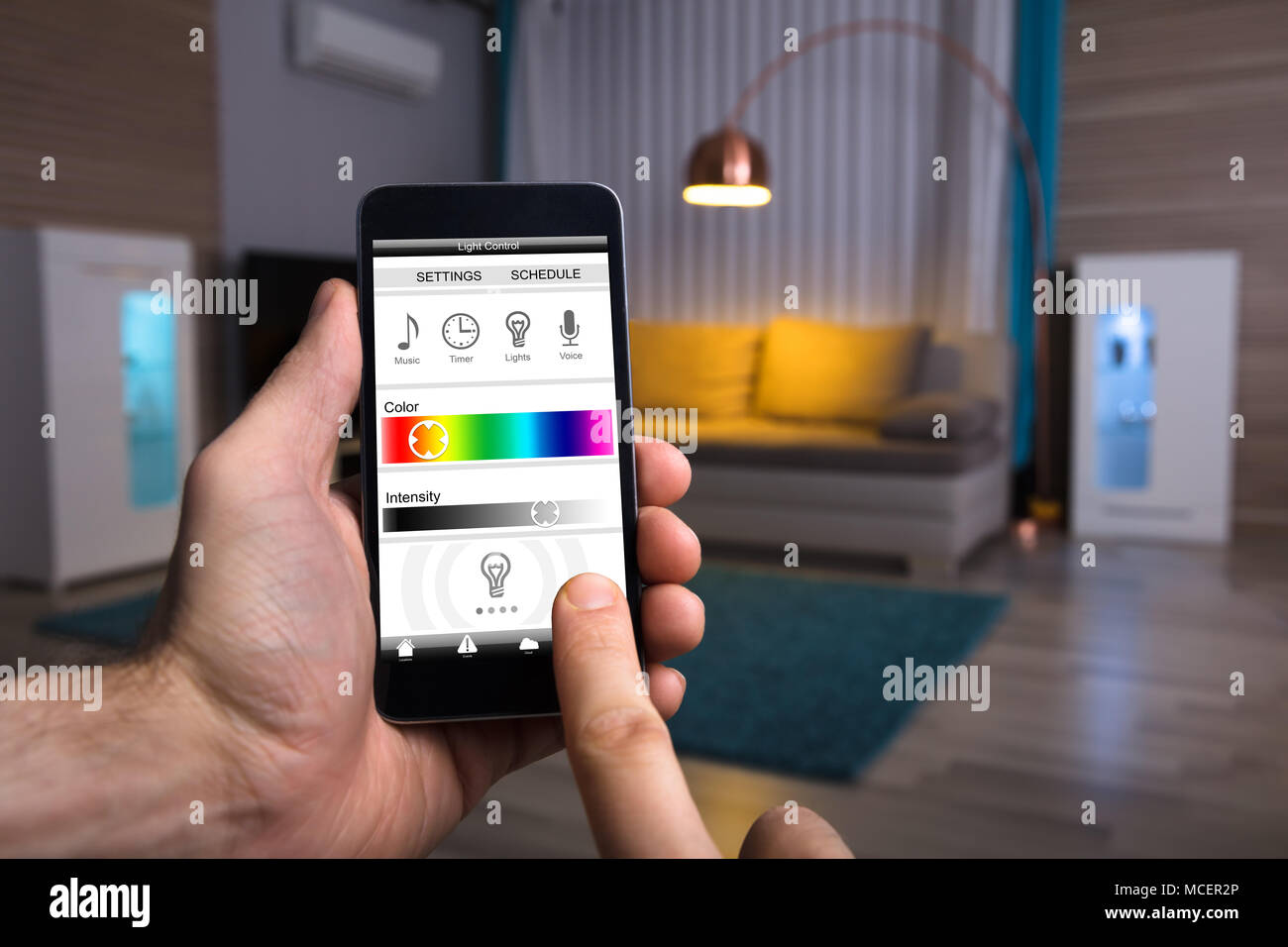 Close-up d'une main humaine La lumière électrique réglage via Mobile Phone At Home Banque D'Images