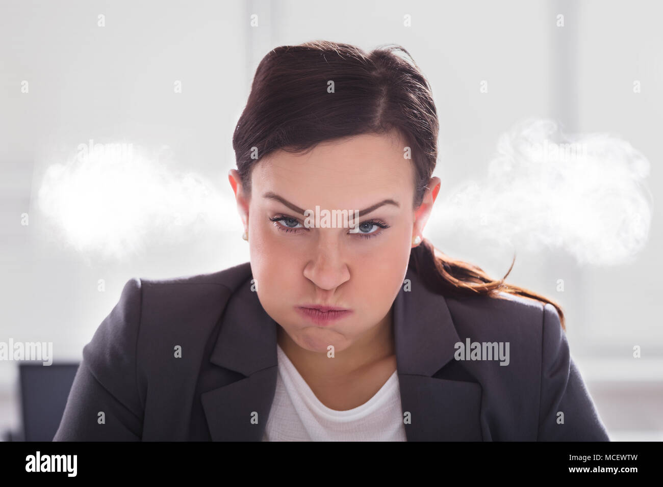 Portrait d'une femme furieuse avec de la fumée sortir de ses oreilles Banque D'Images