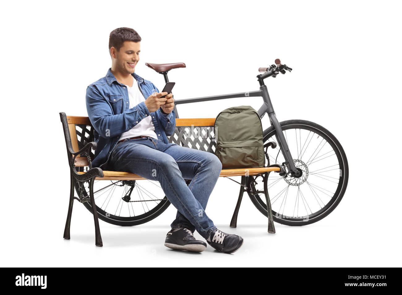 Jeune homme avec un téléphone et un vélo assis sur un banc en bois isolé sur fond blanc Banque D'Images