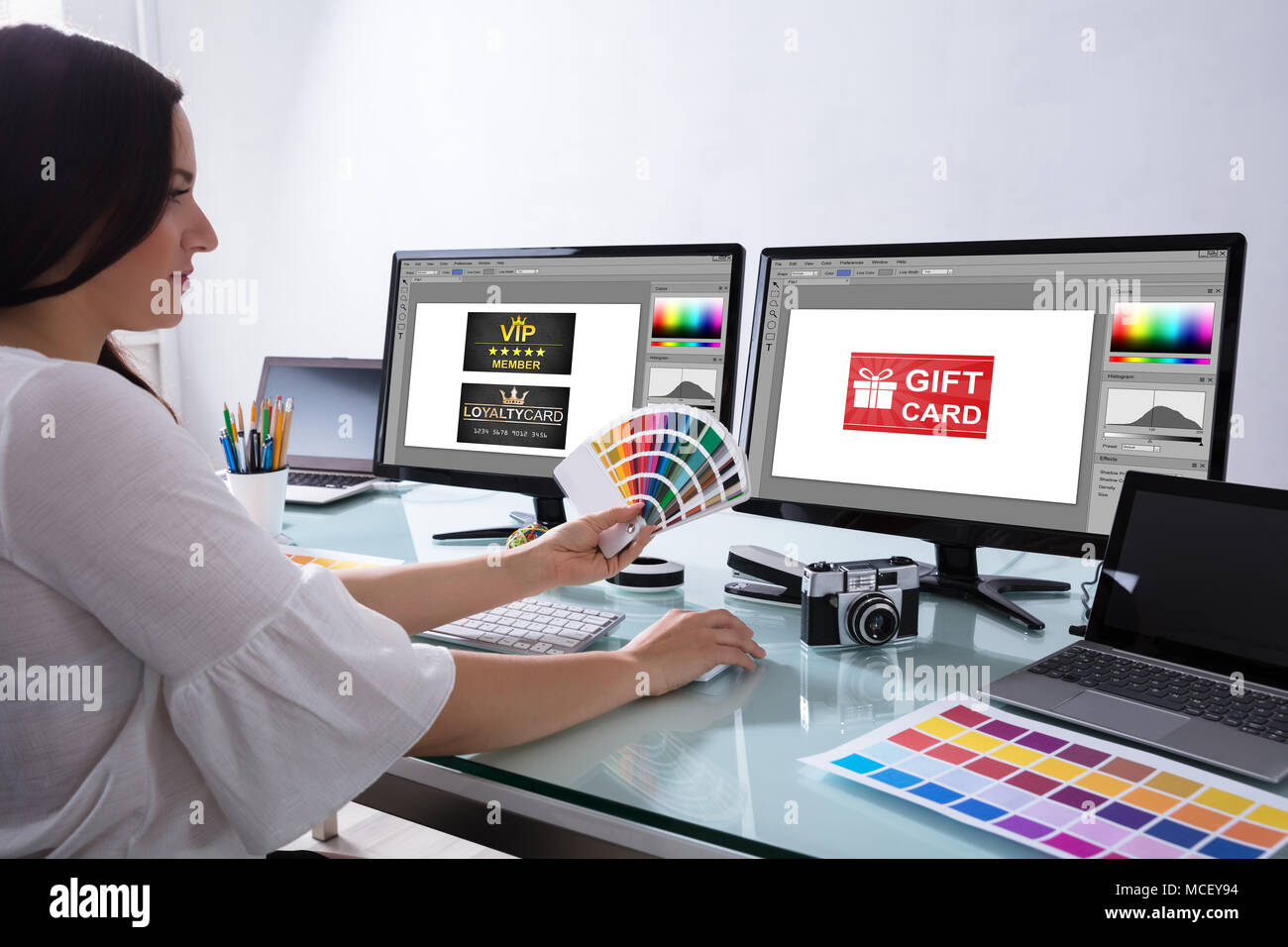 Designer féminin Holding Color Swatch Travailler avec carte-cadeau sur écran d'ordinateur Banque D'Images