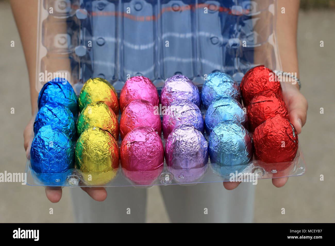 Main tenant les Œufs en chocolat coloré sur carton plastique Banque D'Images