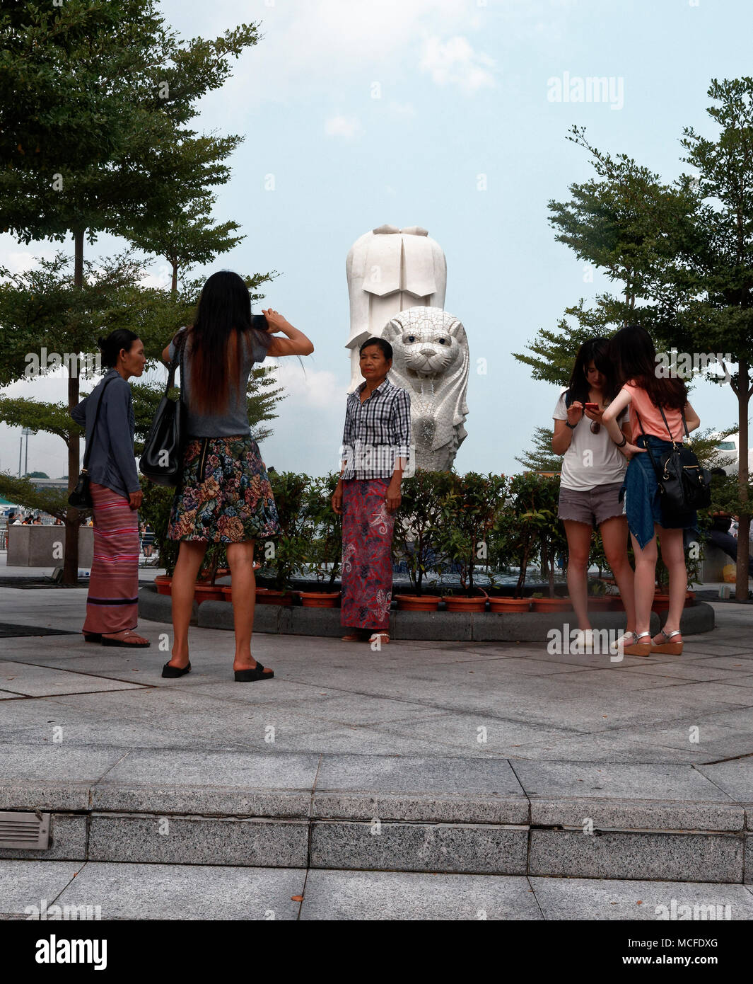 Les touristes asiatiques en prenant des photographies par le mini Merlion à Singapour avec le plus grand derrière. Banque D'Images