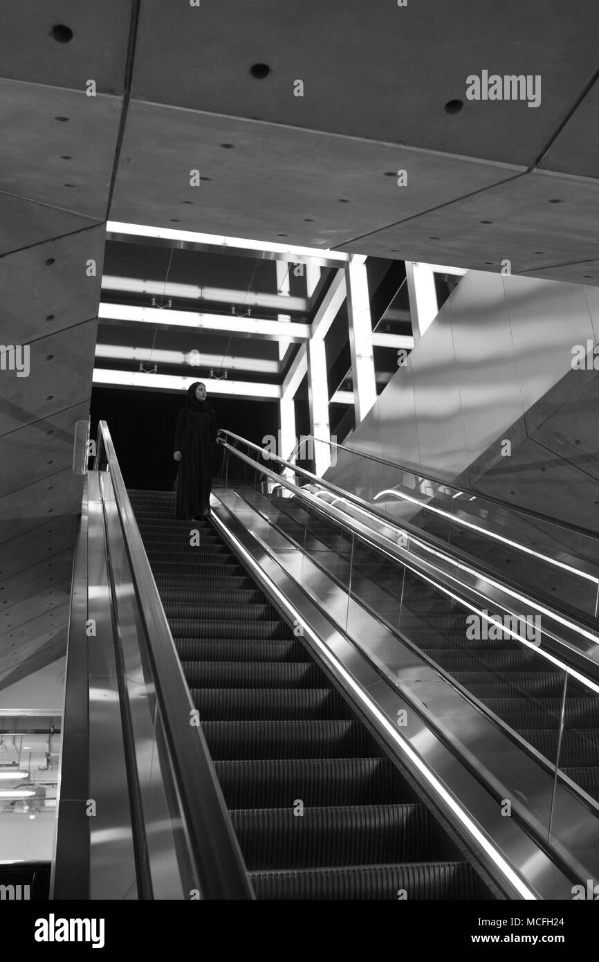 Femme musulmane portant un hijab descend dans l'escalator. Banque D'Images