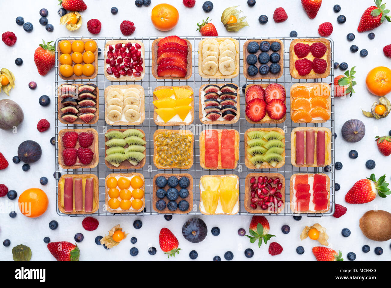 Tartes aux fruits carrés colorés sur une grille de refroidissement sur un fond blanc. Banque D'Images