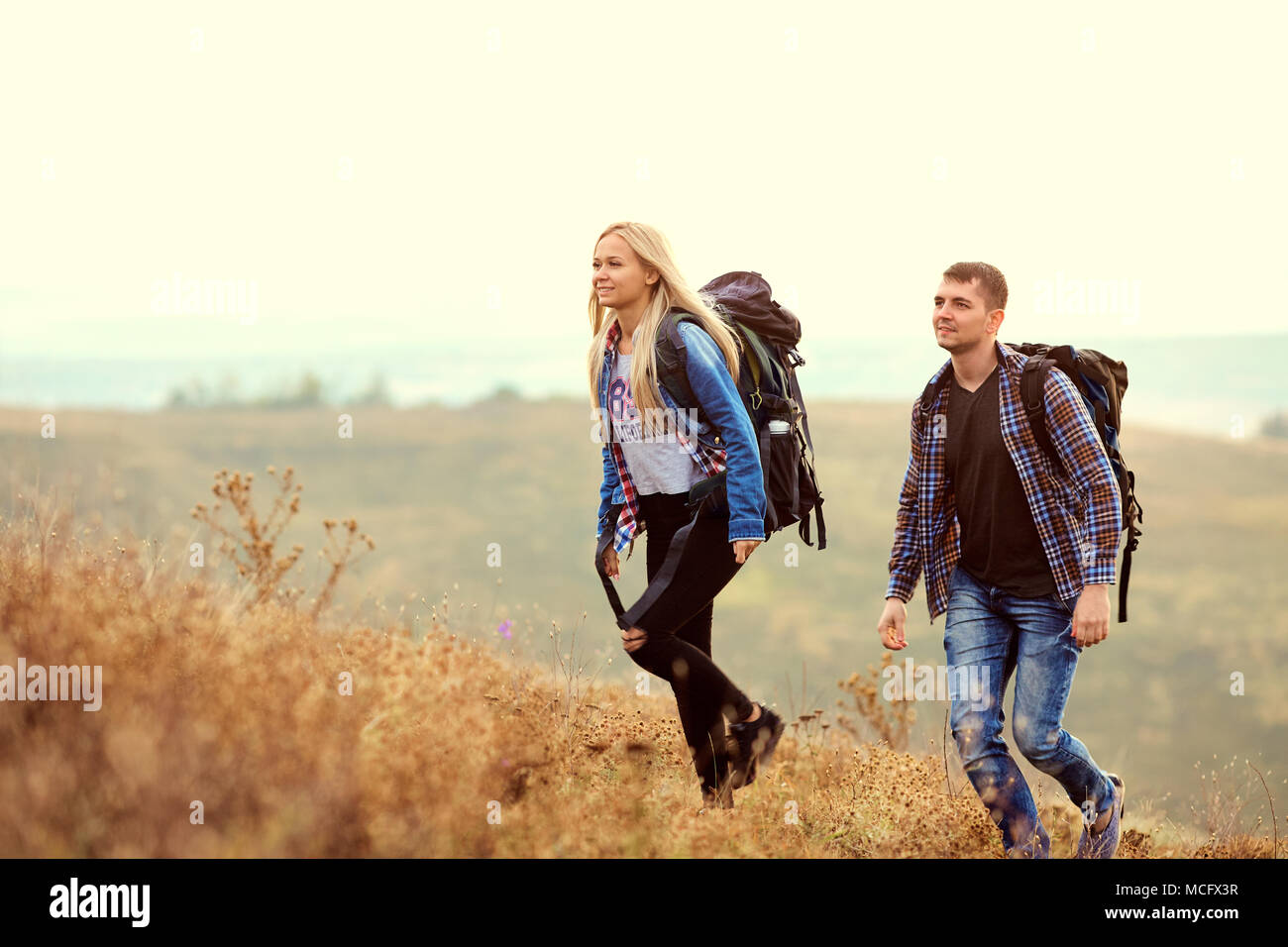 Un jeune couple de touristes avec des sacs à dos sont la marche dans la nature. Banque D'Images