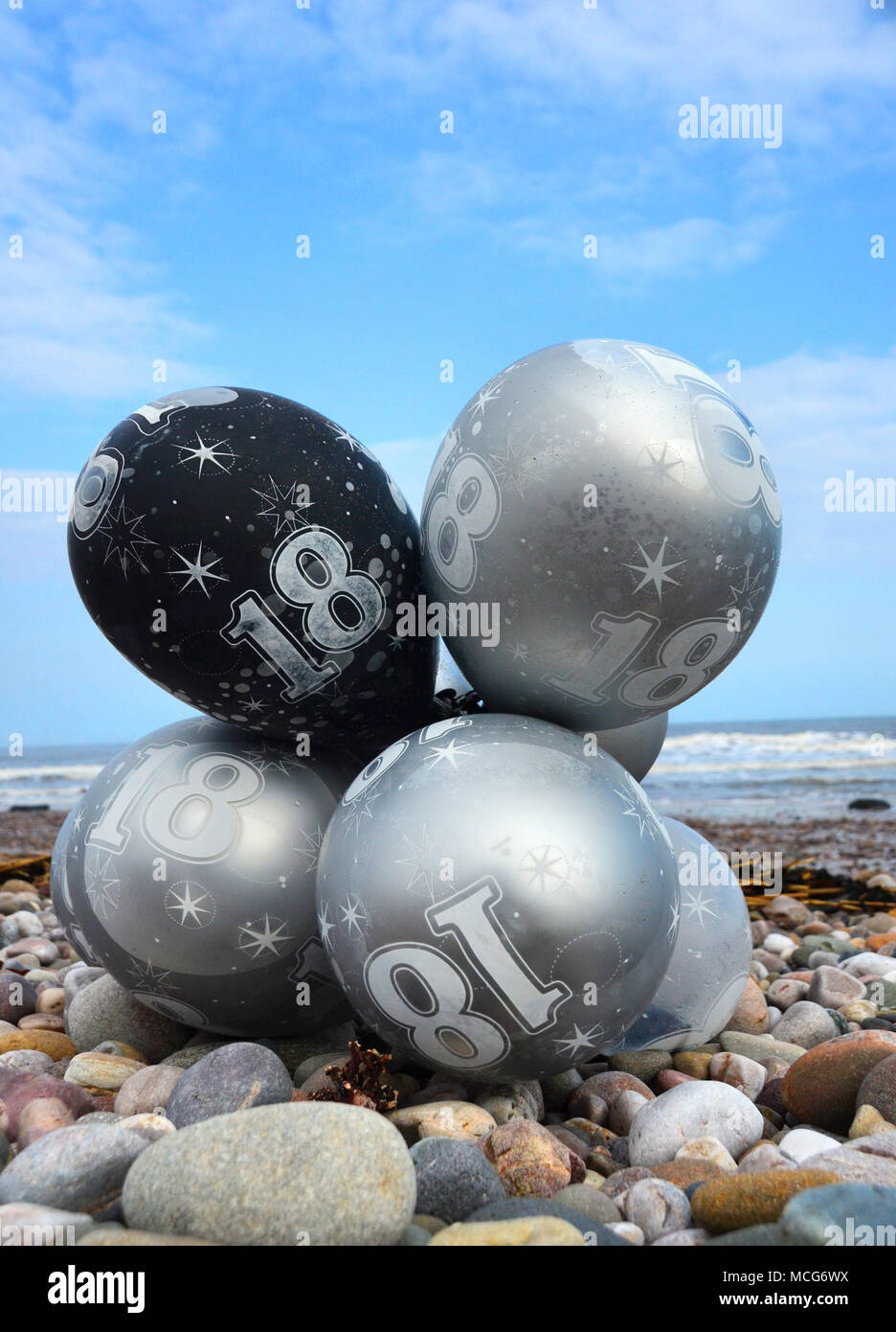 Un faisceau de 18e anniversaire ballons à gaz Hélium qui ont débarqué comme déchets sur une plage. Banque D'Images