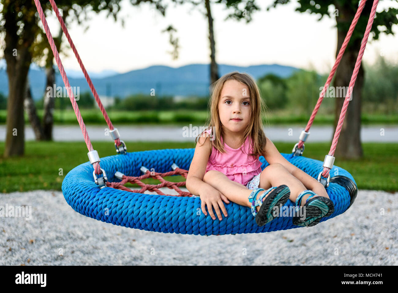 Petit enfant fille sur spider web nest swing sur une aire de jeux. Enfants jouant avec Active Giant Swing-N-Slide Swing Web Monster sur l'extérieur, aire de jeux dans Banque D'Images