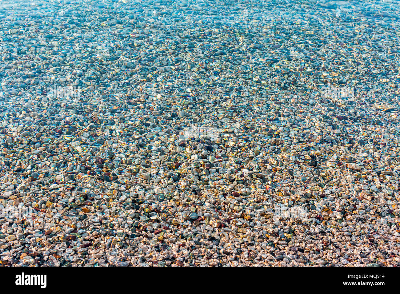 Arrière-plan de la mer de couleurs vives floue des pierres sous l'eau. La lumière du soleil irisé sur les pierres. L'eau de mer claire transparent Banque D'Images