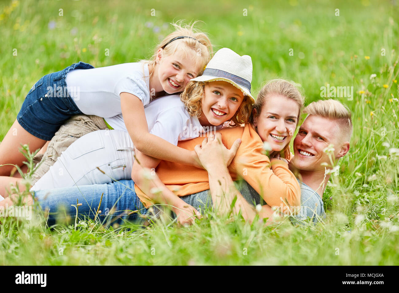Famille et enfants heureux ensemble câlins dans l'herbe dans le jardin Banque D'Images