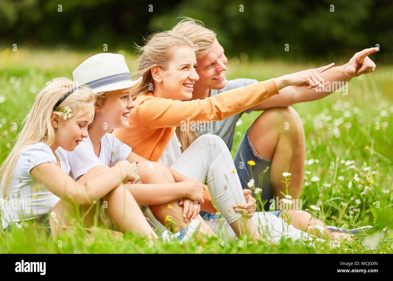 Parents avec enfants détendus dans l'herbe indiquent la direction Banque D'Images
