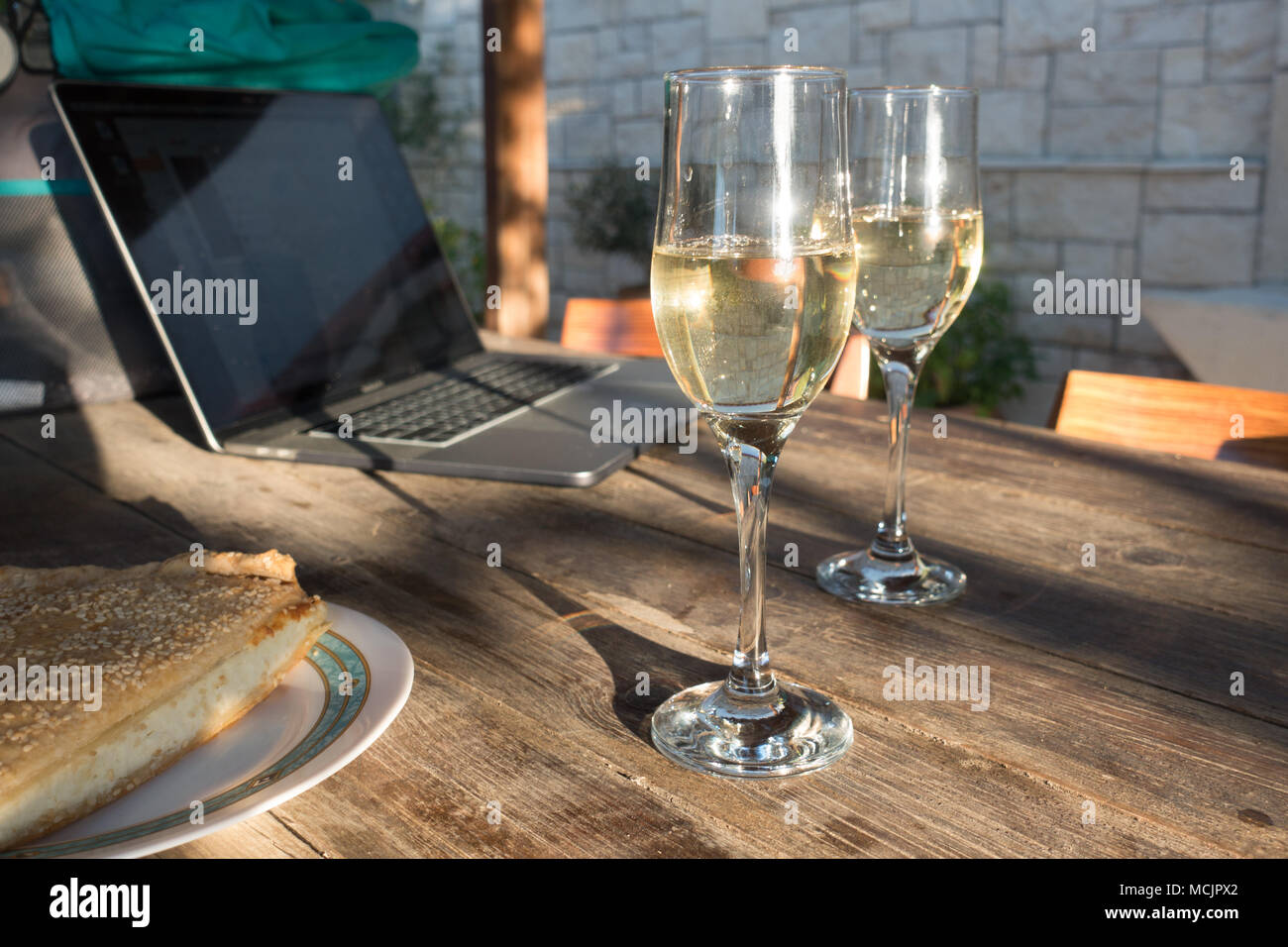 Verres de vin blanc étincelaient sur table de salle à manger avec un ordinateur portable, Crète, Grèce Banque D'Images