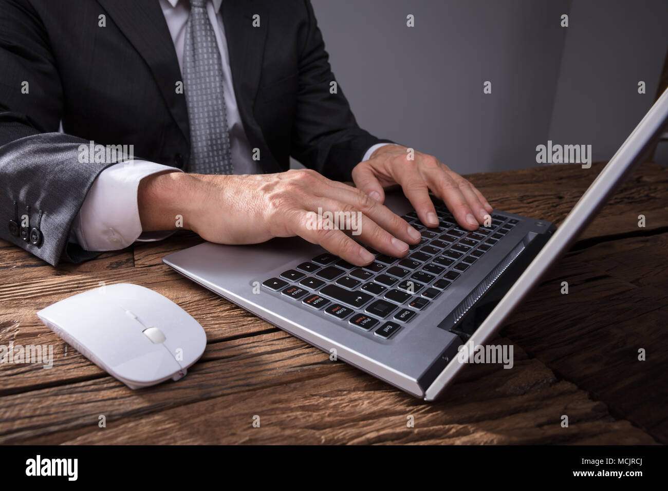 Close-up of a Businessman's Hand en utilisant un ordinateur portable sur un bureau en bois Banque D'Images