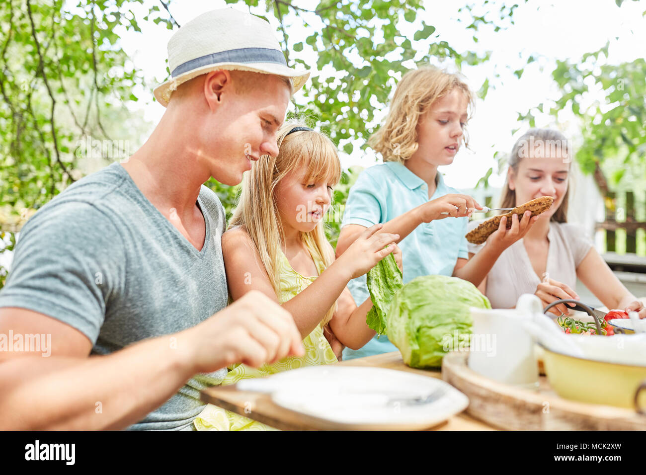 Famille et enfants prennent le petit déjeuner ensemble dans le jardin en été Banque D'Images