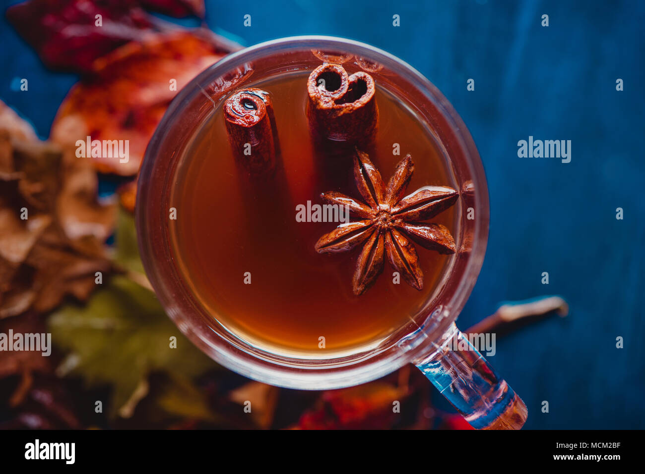 Tasse de thé à l'anis étoile et la cannelle close-up. Hors focus automne fond avec des feuilles et des baies. Rainy day concept avec copie espace. Banque D'Images