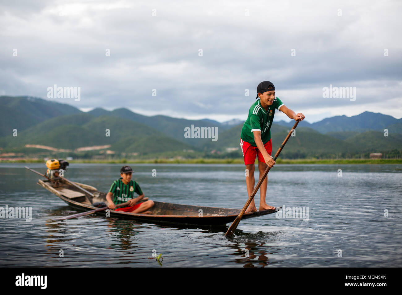 Deux garçons pagayer dans bateau sur le lac Inle, l'État de Shan, Myanmar Banque D'Images