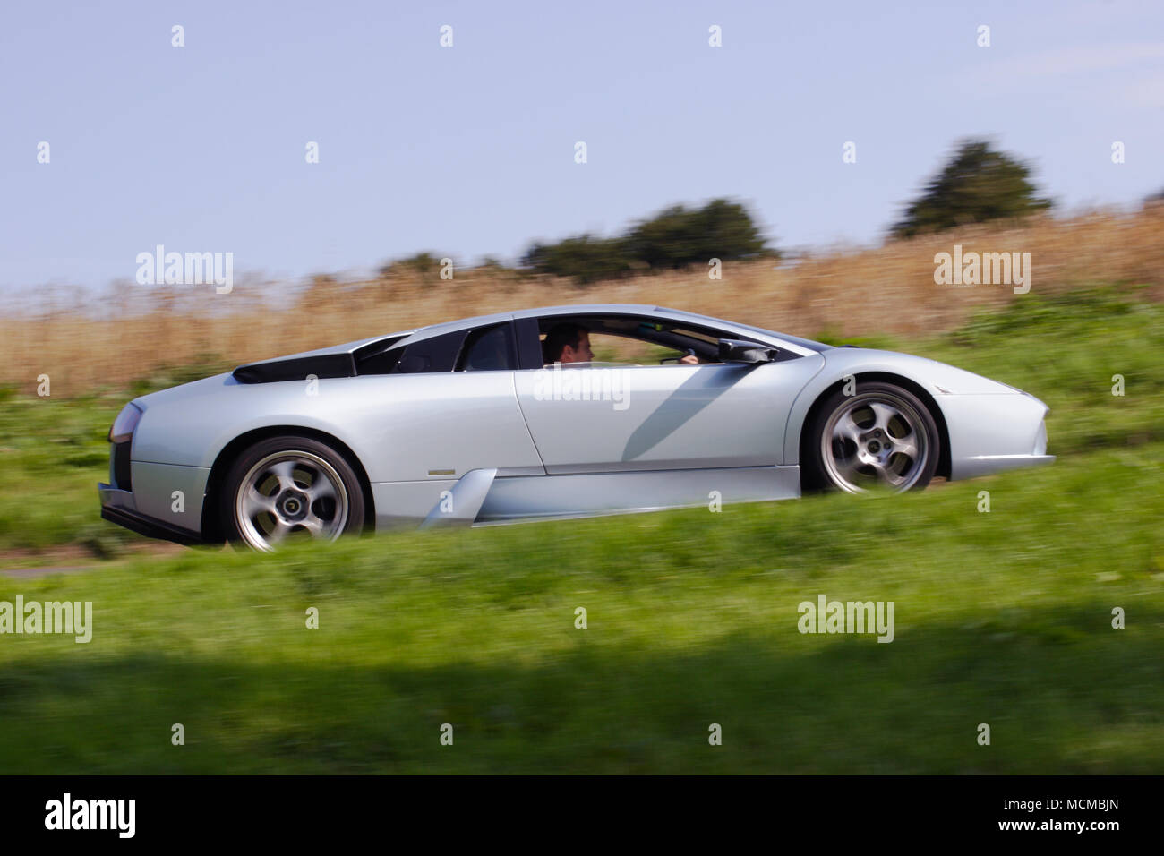 Profil de l'angle faible (vue de côté) d'une Lamborghini Murciélago supercar hypercar argent conduite rapide. Banque D'Images