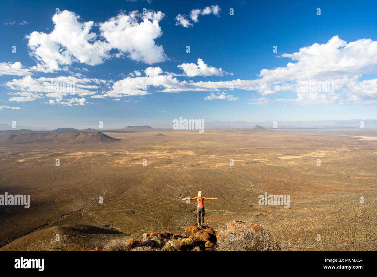 Une femme debout sur le bord d'une falaise étant immergée dans le paysage pittoresque du Tankwa Karoo, Western Cape, Afrique du Sud Banque D'Images