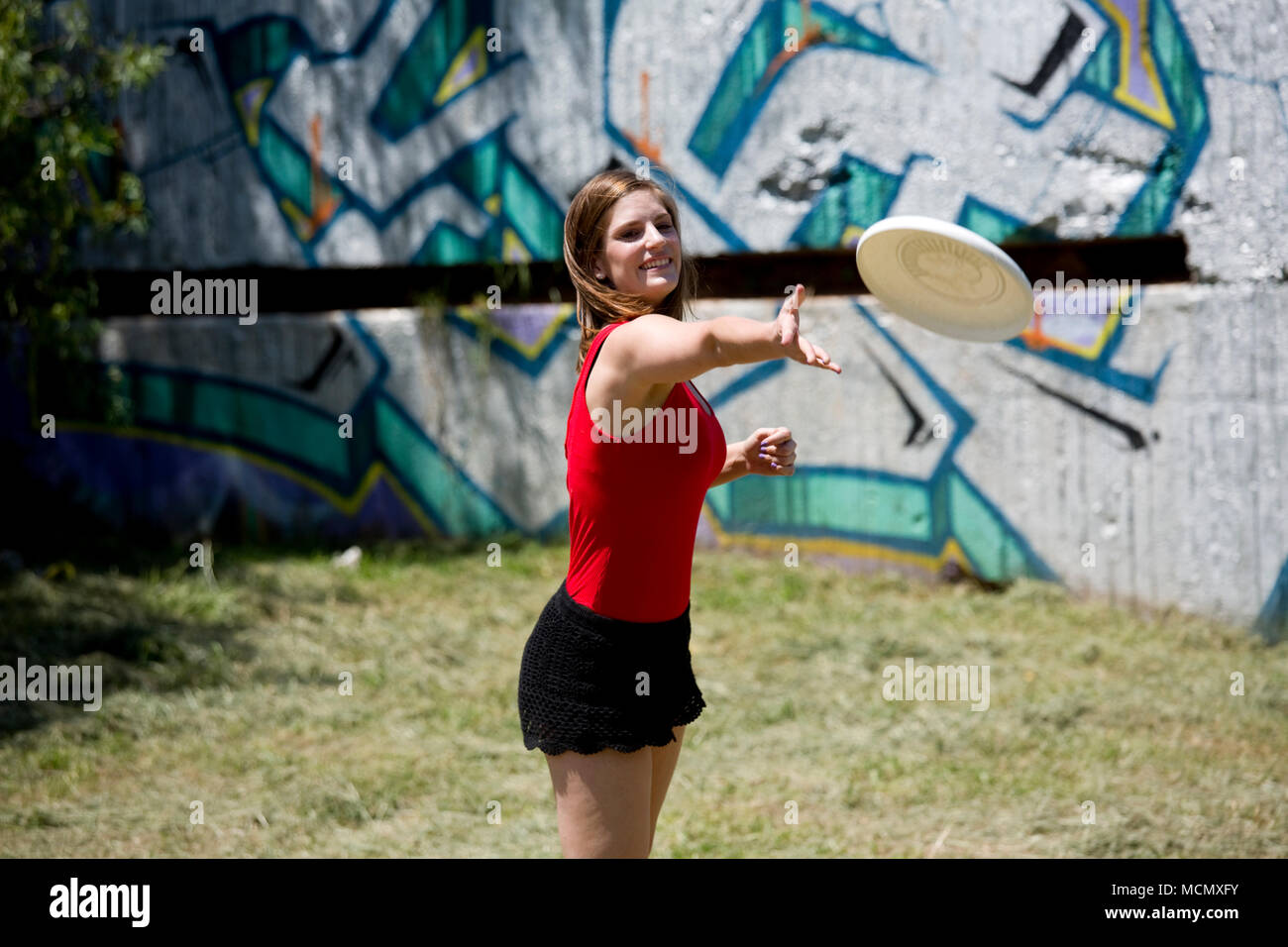 Femme throughing un frisbee dans le parc Banque D'Images