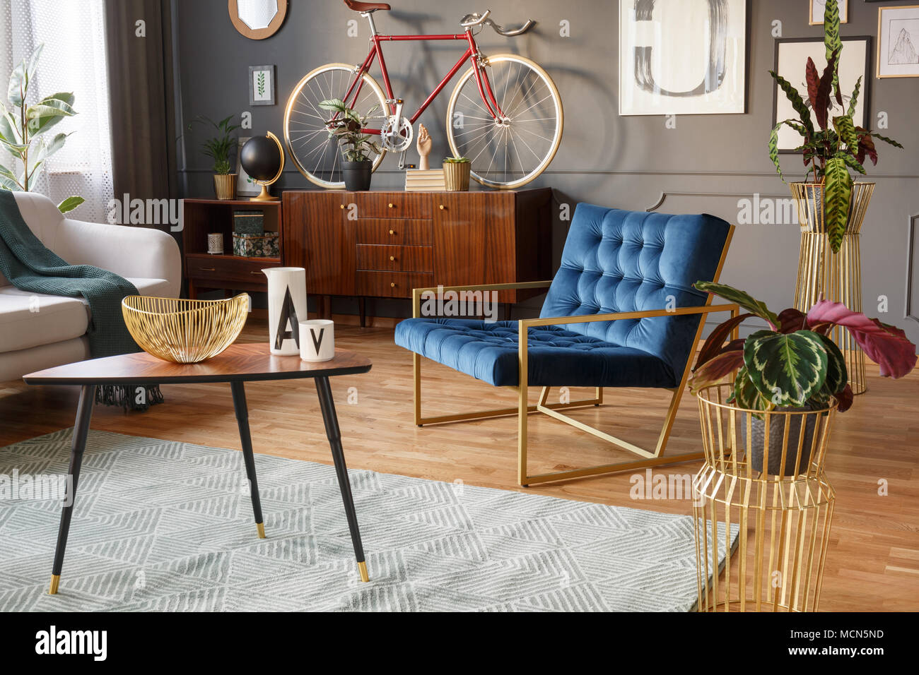 Plantes en pots d'or, table basse en bois avec décorations et fauteuil bleu dans un salon vintage interior Banque D'Images