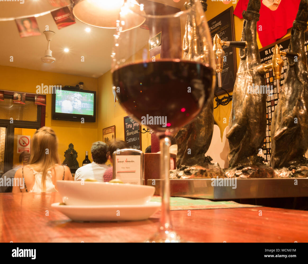 Ceux qui suivent le football à la télévision en espagnol bar. Verre de vin rouge en premier plan Banque D'Images