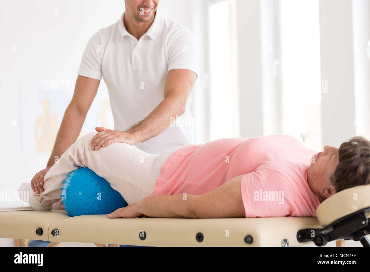 Smiling therapist massaging une vieille femme à l'ostéoporose à l'aide  d'une boule bleue Photo Stock - Alamy