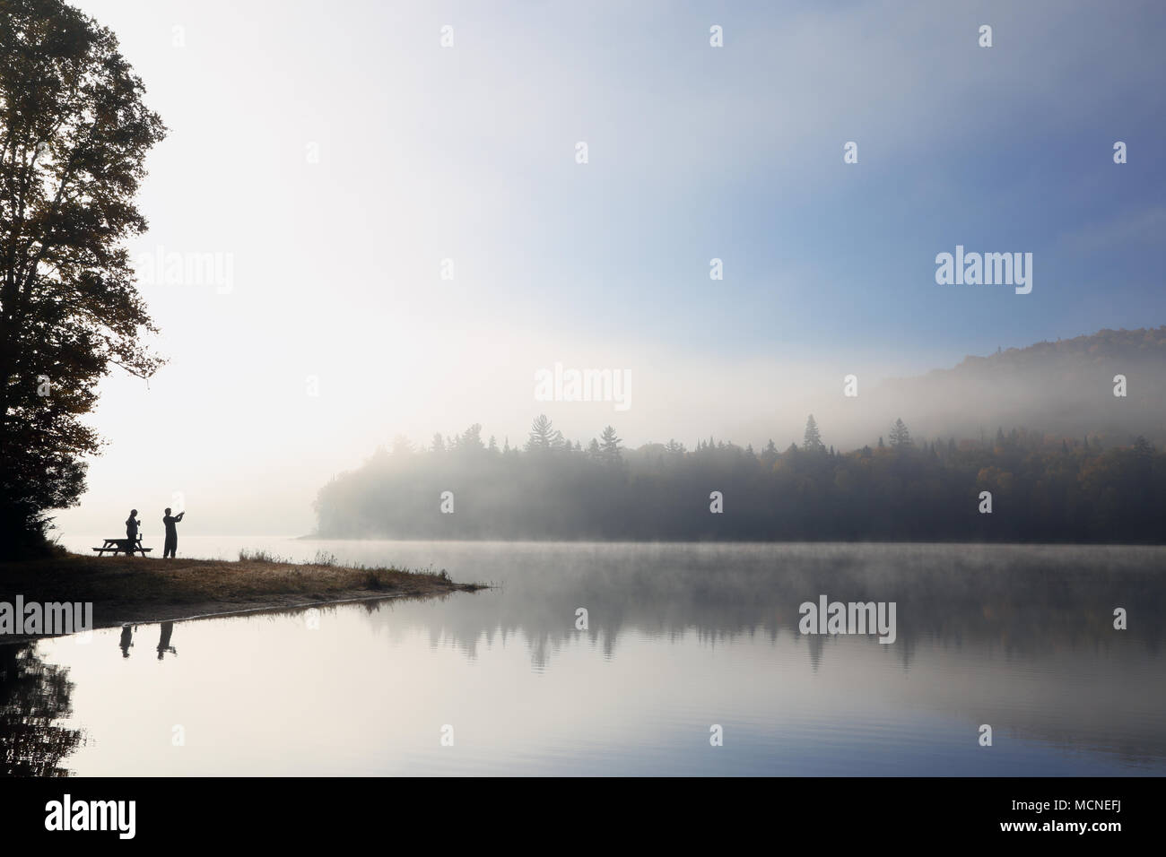 Silhouette. Matinée de détente sur le lac. La sérénité. Le brouillard sur le lac. Lever de Soleil sur le lac de montagne. Les gens de silhouettes. Paysage d'automne. Banque D'Images