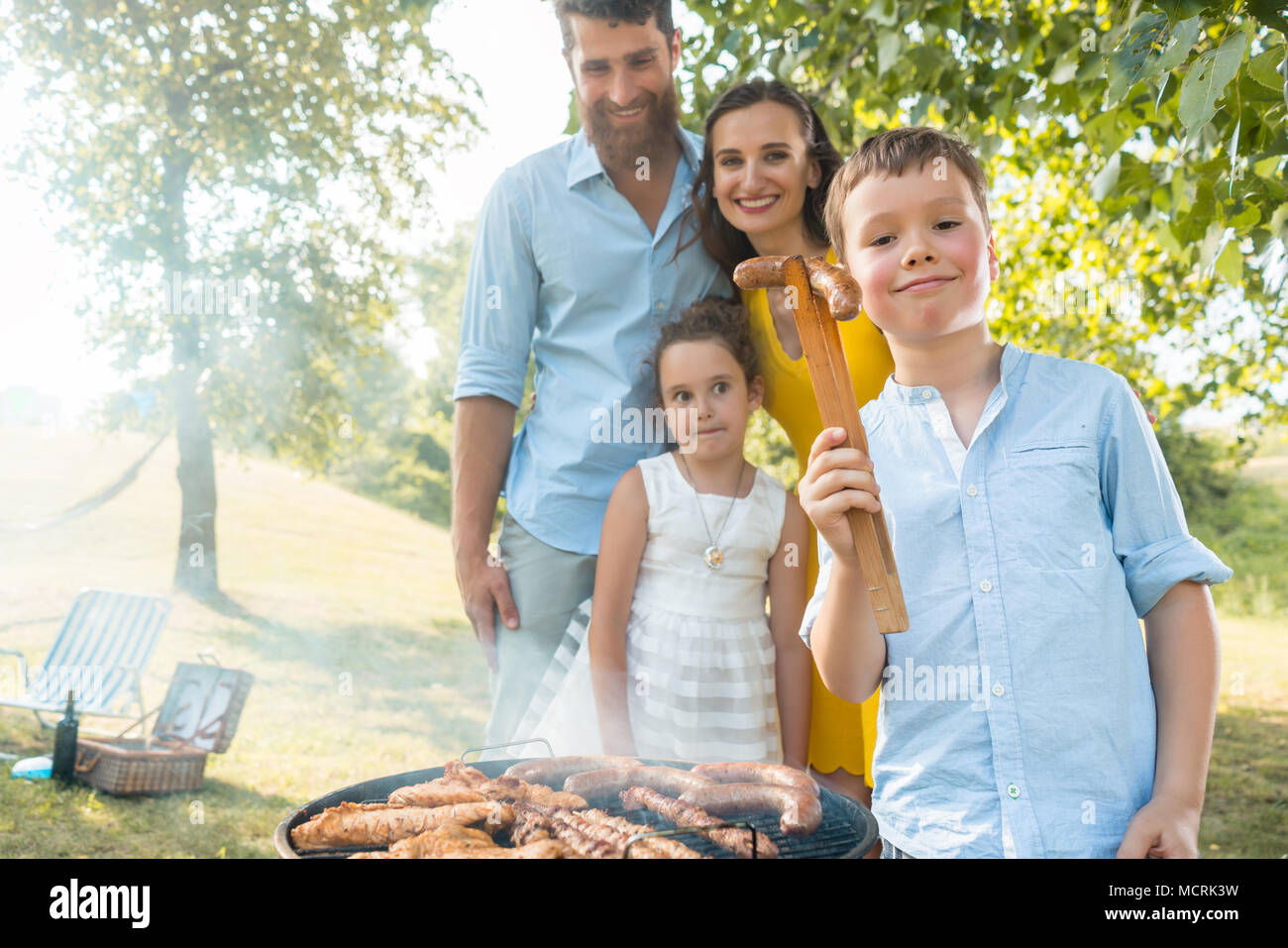 Portrait de famille heureuse avec deux enfants à l'extérieur près du barbecue Banque D'Images