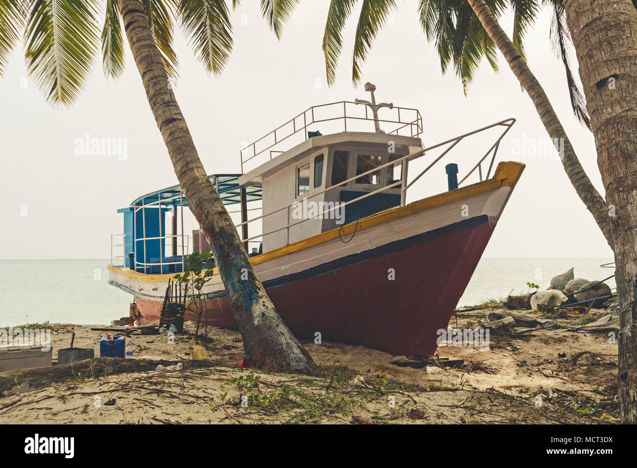 Naufrage sur une plage. Grand bateau de pêche sur le sable sur la plage sous les palmiers sur l'île des Indiens. Le bateau est en réparation au quai. Banque D'Images