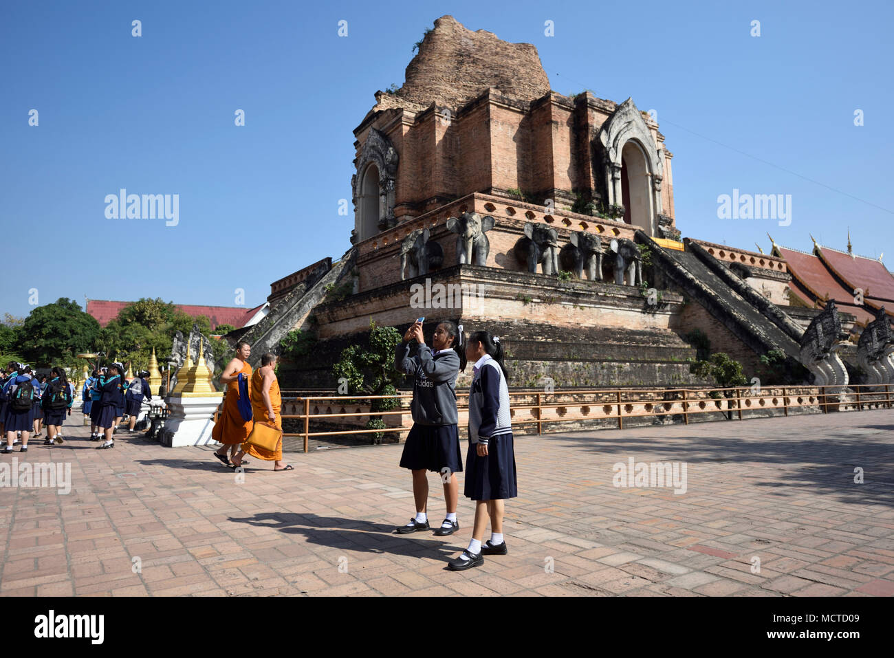 Écolières et moines au temple Wat Chedi Luang, Chiang Mai, Thaïlande Banque D'Images