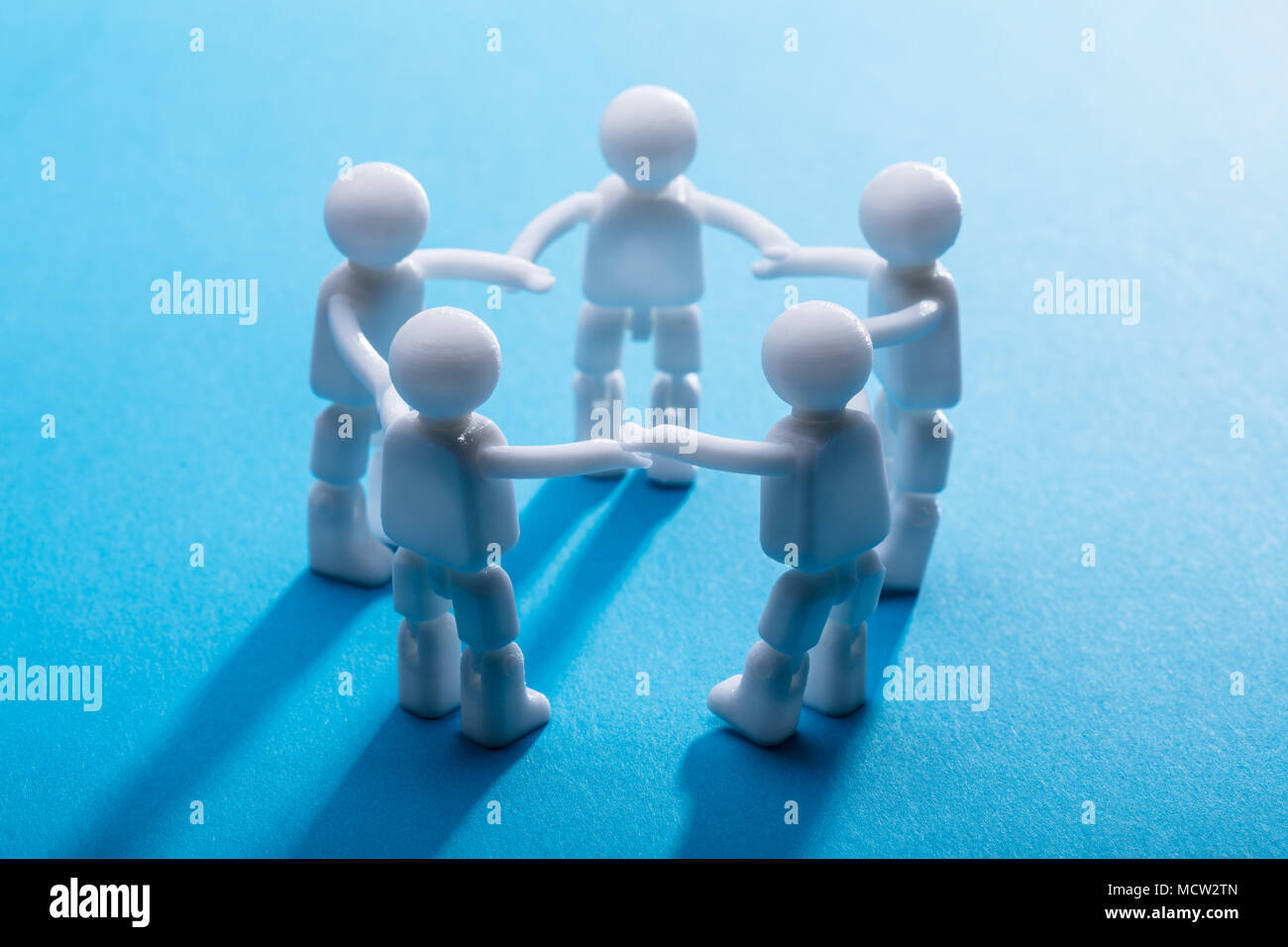 Close-up de figures humaines se tenant la main debout sur fond bleu Banque D'Images