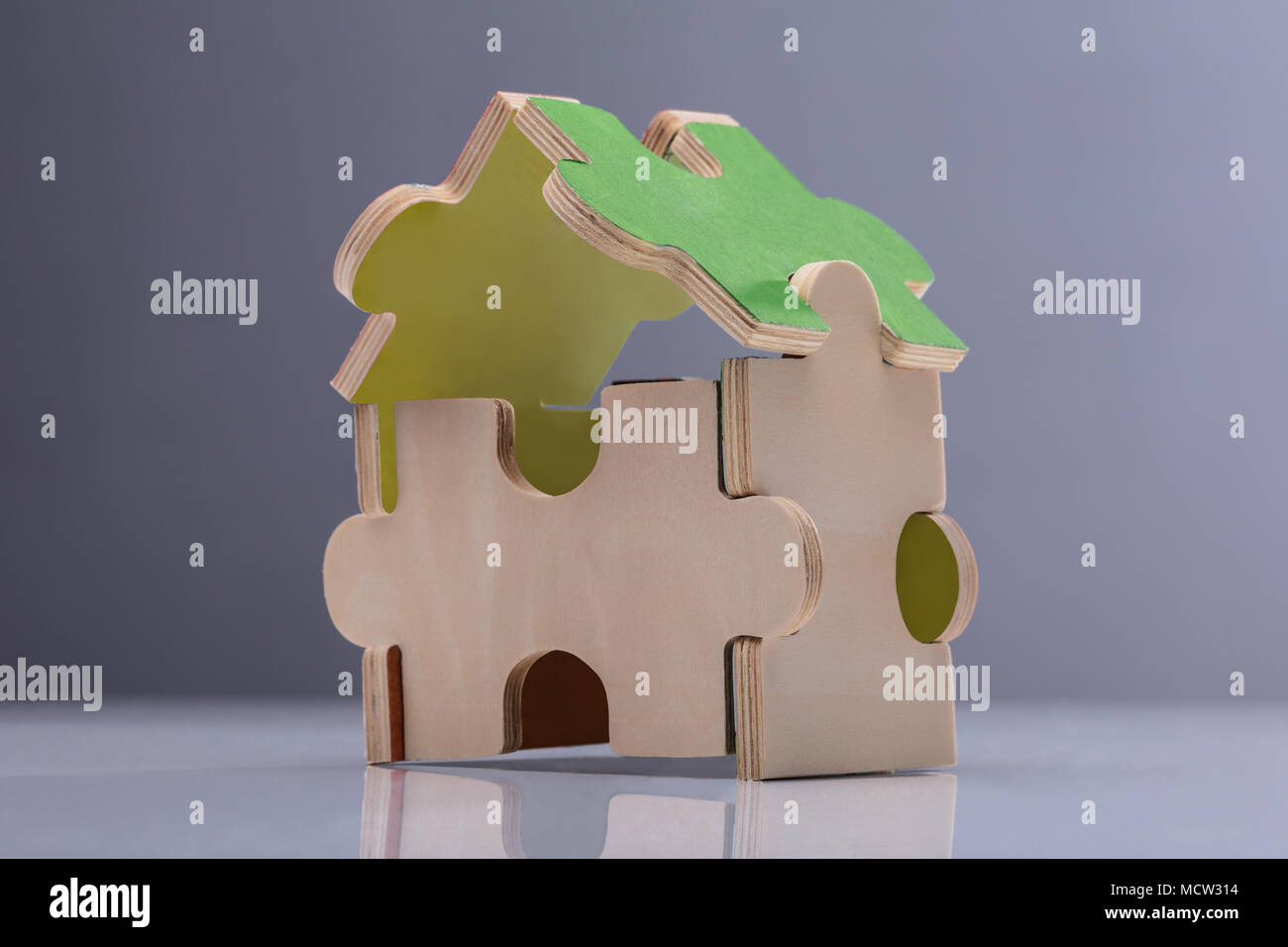 Modèle de maison composé de Puzzle contre l'arrière-plan gris Banque D'Images