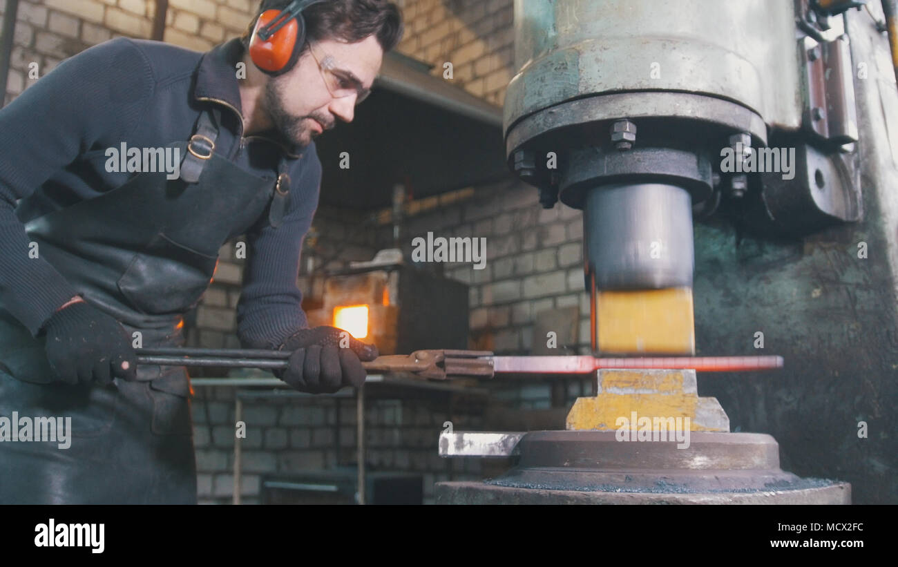 Blacksmith forge fer chaud rouge sur enclume - martelage automatique Banque D'Images
