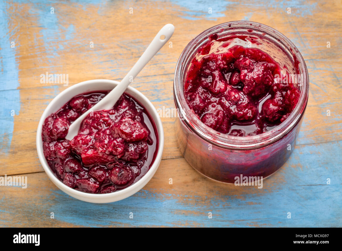 Tout fait maison sauce canneberges - bocal de verre et petit bol en céramique sur un bois grunge Banque D'Images